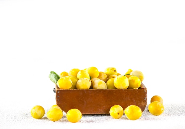 신선한 노란색 자두입니다. 흰색 바탕에 나무 상자에 익은 과일.