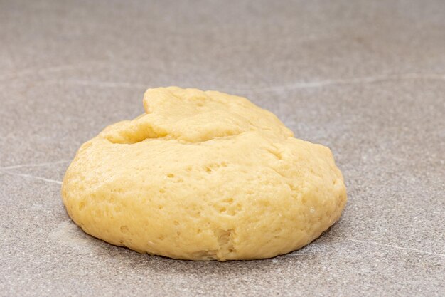 Fresh yellow raw dough in the shape of a ball for baking gingerbread men for Christmas on a gray background. The process of making cookies at home. Christmas tradition concept