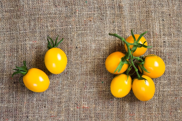 Fresh yellow tomatoes on sackcloth surface