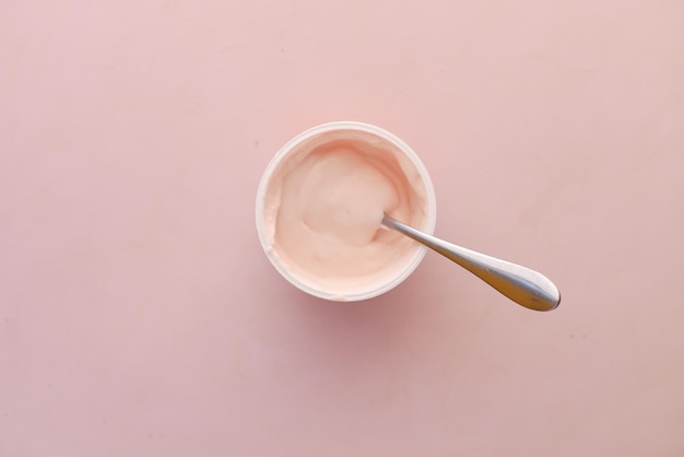 Fresh yogurt in a plastic container and spoon on table