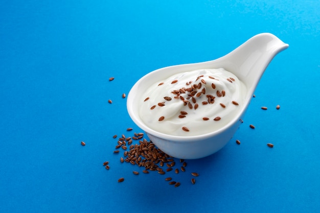 Fresh yogurt with flax seeds isolated on blue