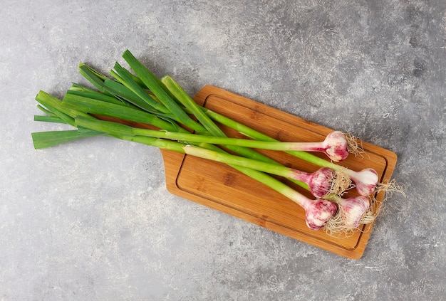 Fresh young garlic with leaves on a cutting board gray table top view horizontal no people