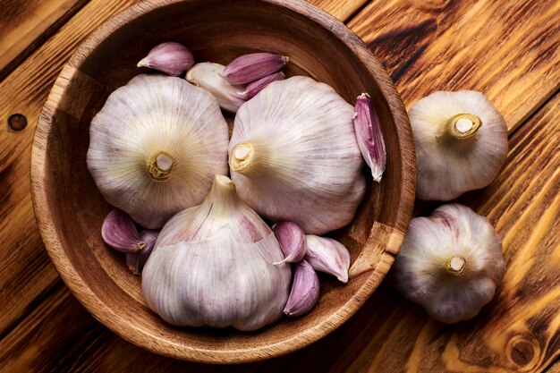 Fresh young garlic in a wooden cup on a wooden table.