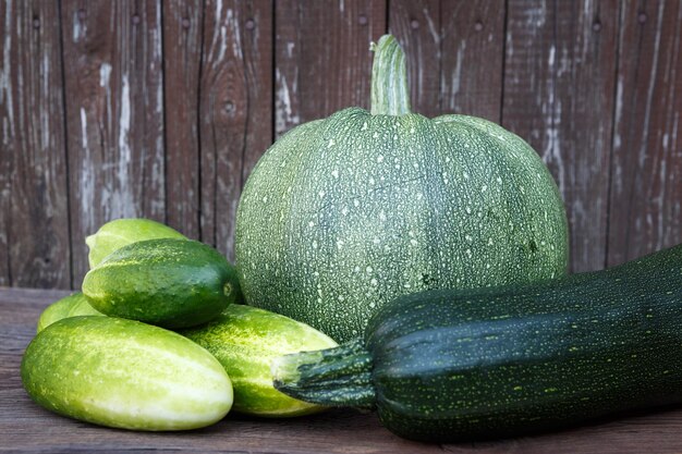 Fresh zucchini and cucumbers on the wooden table Bio vegetables on a wooden background