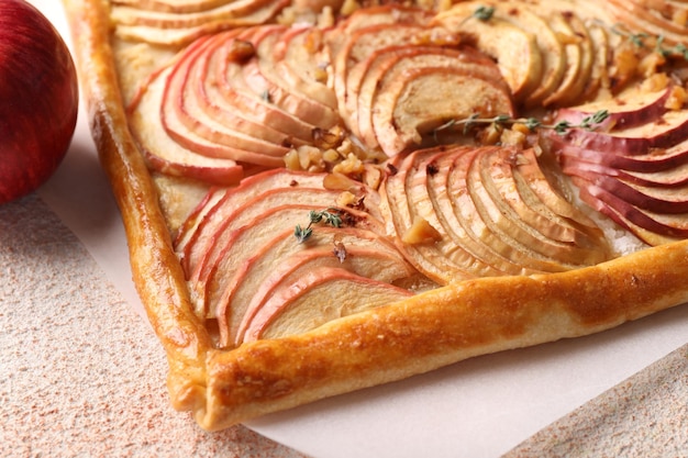 Foto torta di mele appena cotta con noci su tavolo a consistenza beige in primo piano