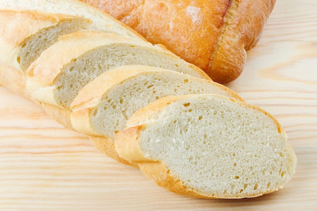 Freshly baked baguette sliced on wooden cutting board