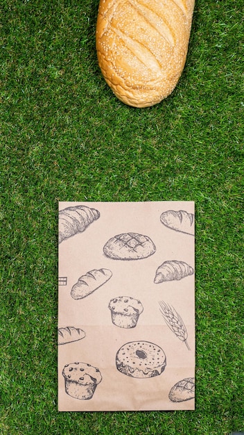 Freshly baked bread and crumpled paper bag on a grass background Top view