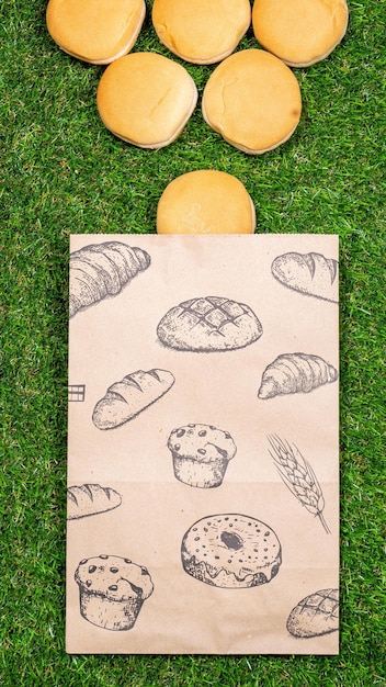 Freshly baked bread and crumpled paper bag on a grass background Top view