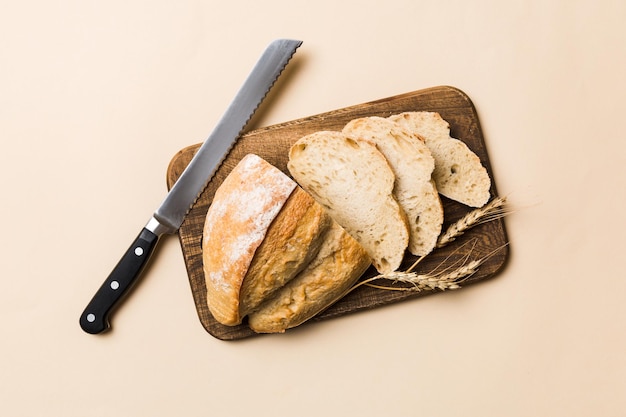 Pane appena sfornato tagliato con un coltello su una tavola di legno vista dall'alto pane a fette e coltello