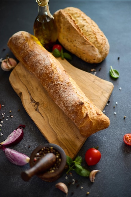 Фото Свежевыпеченный хлеб на деревянной доске для резки на темном столе