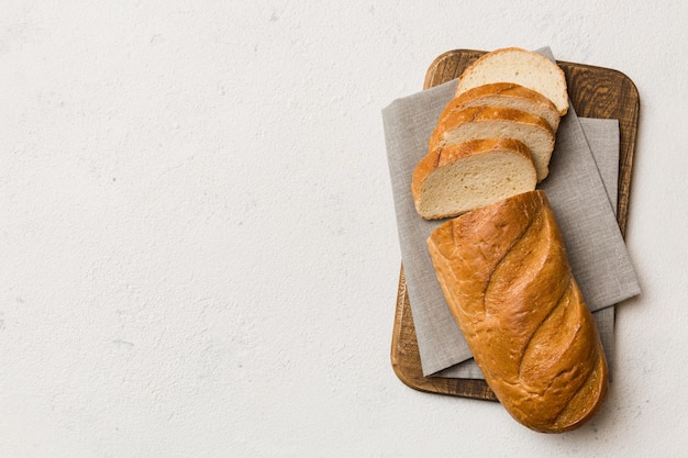 Freshly baked bread slices on cutting board against white wooden background top view Sliced bread