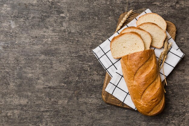 白い木製の背景に対してまな板で焼きたてのパンのスライス上面図スライスされたパン