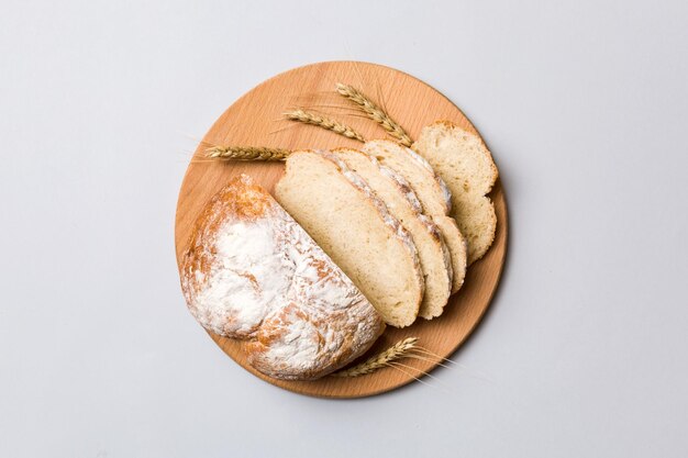 Freshly baked bread slices on cutting board against white wooden background top view Sliced bread