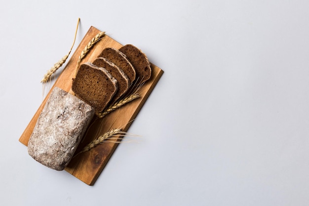 Freshly baked bread slices on cutting board against white wooden background top view Sliced bread