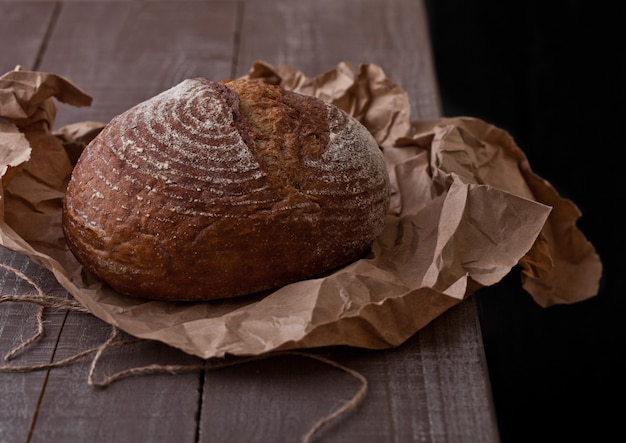 Freshly baked  bread with on brown oven paper on wooden board