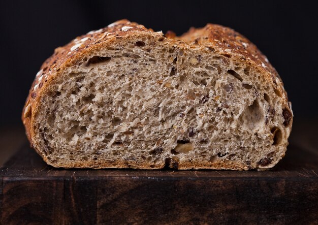 Freshly baked  bread with oats on wooden board background