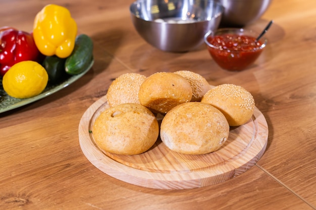 Freshly baked burger buns with sesame seeds in kitchen