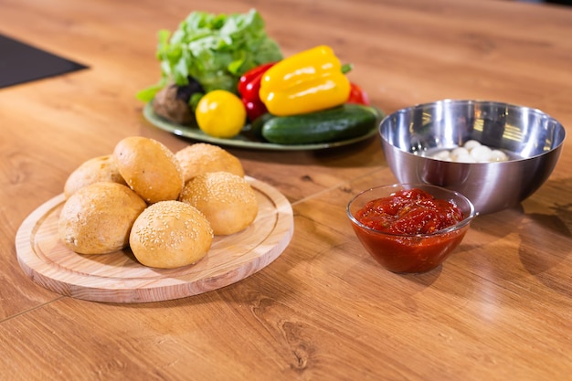 Freshly baked burger buns with sesame seeds in kitchen