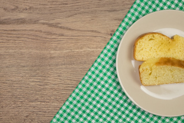 Freshly baked cake slices and green tablecloth on wooden table