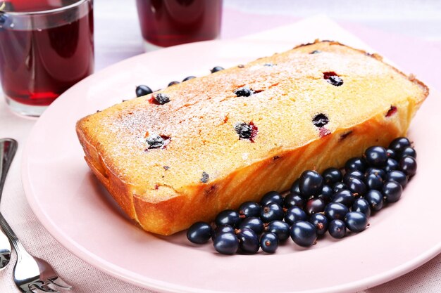 Freshly baked cake with black currants in pink plate closeup