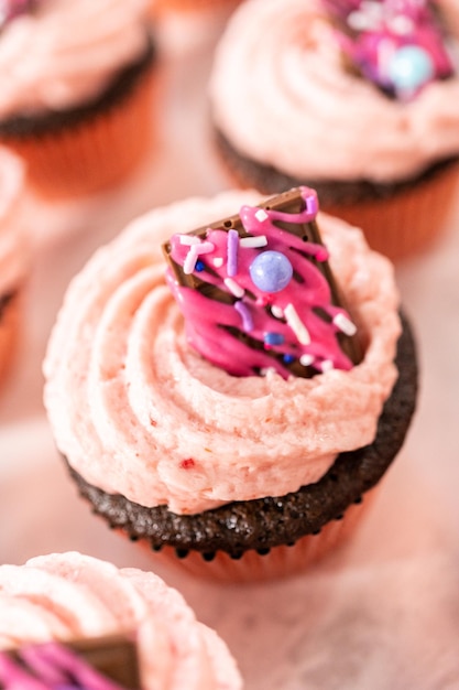 Freshly baked chocolate strawberry cupcakes garnished with gourmet mini pink chocolates