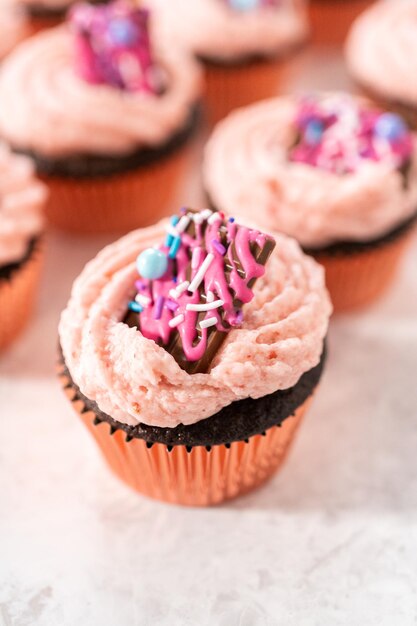 Freshly baked chocolate strawberry cupcakes garnished with gourmet mini pink chocolates