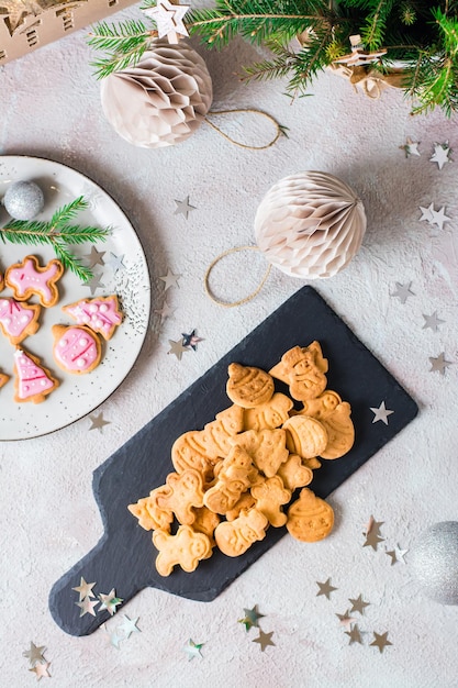 Freshly baked Christmas cookies are piled on a slate on a decorated table. Festive treat. Top and vertical view