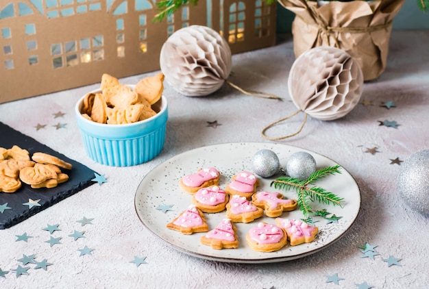 Freshly baked Christmas cookies with pink icing on a plate on a decorated table. Festive treat