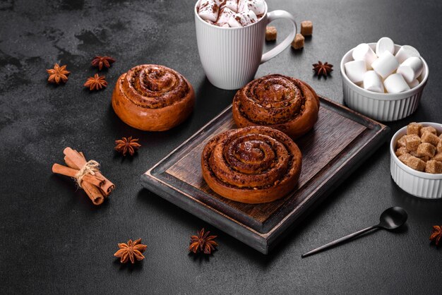 Freshly baked cinnamon roll with spices and cocoa filling on a black background. Cinnabon buns. Swedish breakfast.