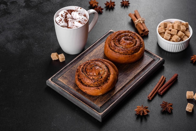 Rotolo di cannella appena sfornato con spezie e ripieno di cacao su sfondo nero. panini alla cannella. colazione svedese.