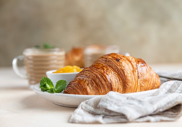 Freshly baked crispy french croissants with jam and chocolate cream and two coffee cups Breakfast