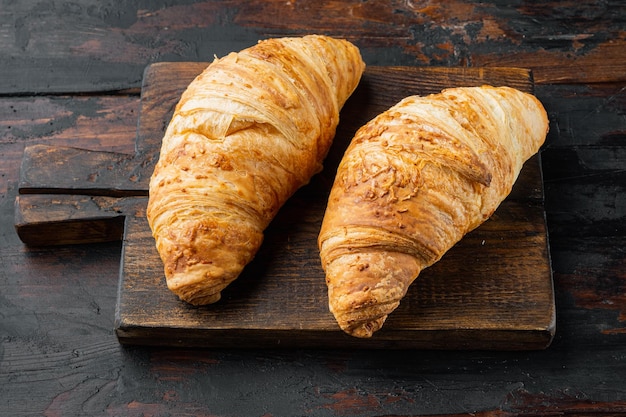 Freshly baked croissants on old dark wooden table background