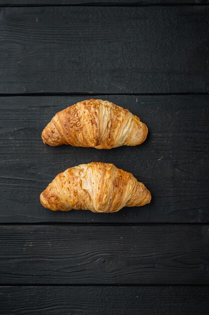 Freshly baked croissants set, on black wooden table background, top view flat lay