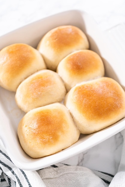 Freshly baked dinner rolls in a white ceramic dish