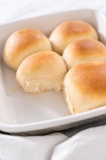 Freshly baked dinner rolls in a white ceramic dish.