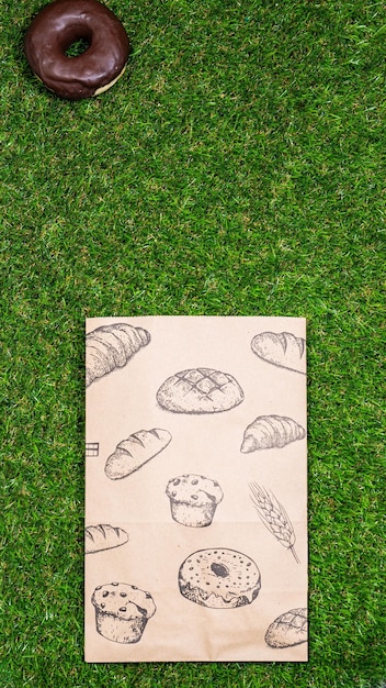 Freshly baked donuts and crumpled paper bag on a grass background Top view