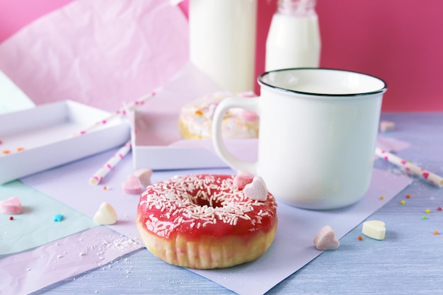 Freshly baked donuts glazed and sprinkled with caramel hearts milk and yogurt in a cup