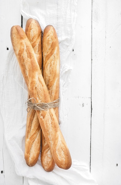 Freshly baked French baguettes on white wooden table Top view