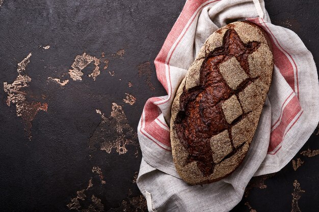 Photo freshly baked homemade bread on artisan sourdough rye on brawn stone or concrete background. top view. food cooking background. copy space.