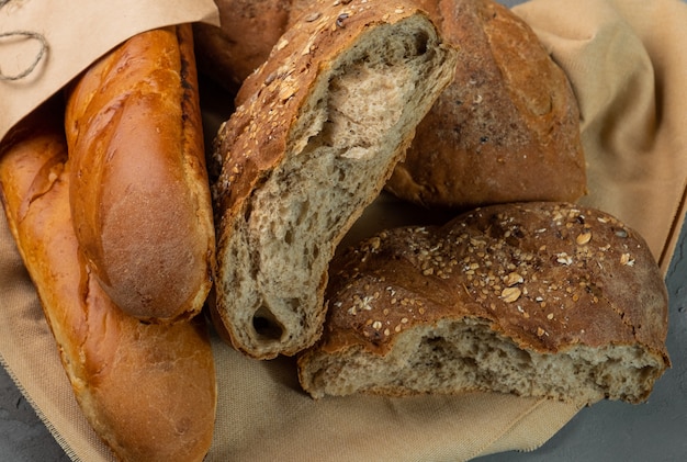 Freshly baked homemade bread, whole and broken pieces. Bread lies on the fabric.