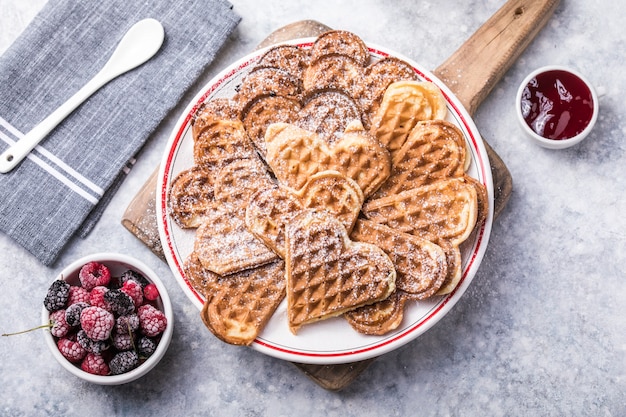 Freshly baked homemade heart shaped Belgium waffles on gray background. European baked pastry sweets