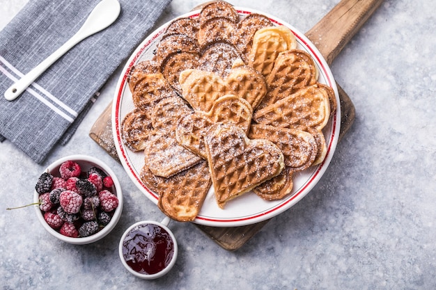 Freshly baked homemade heart shaped Belgium waffles on gray background. European baked pastry sweets