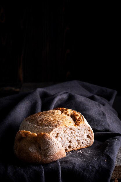 Freshly baked homemade sour dough bread on dark linen napkin, wooden background.