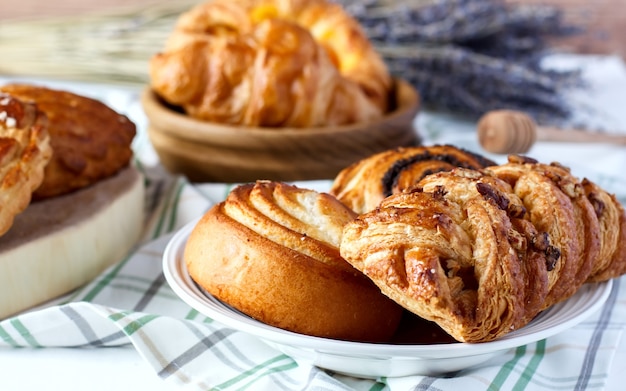 Freshly baked homemade sweet buns with poppy seeds and honey on table in saucer