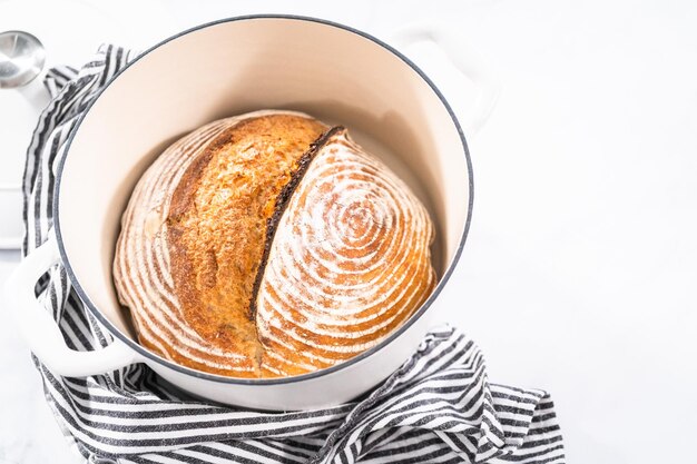 Freshly baked loaf of a wheat sourdough bread with marks from bread proofing basket in enameled cast iron dutch oven