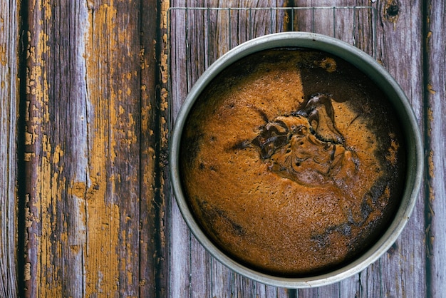 Freshly baked marbled sponge cake cooling on wooden table