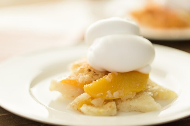 Freshly baked peach cobbler with scoop of whipped cream.