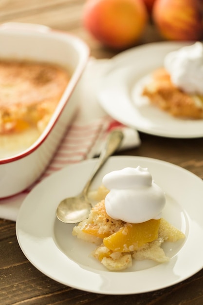 Freshly baked peach cobbler with scoop of whipped cream.