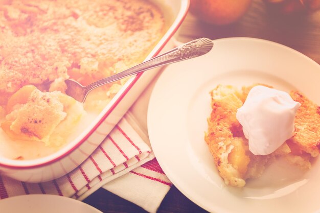 Freshly baked peach cobbler with scoop of whipped cream.