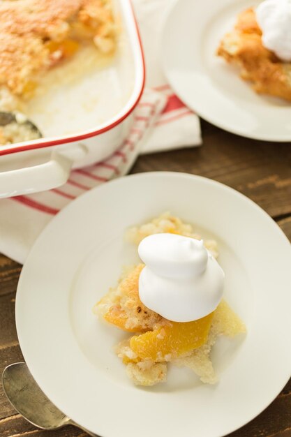 Freshly baked peach cobbler with scoop of whipped cream.